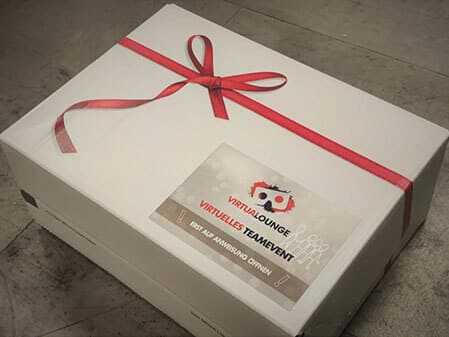 Goodie Box Karton in weiß mit roter Schleife für die virtuelle Weihnachtsfeier von der VirtuaLounge